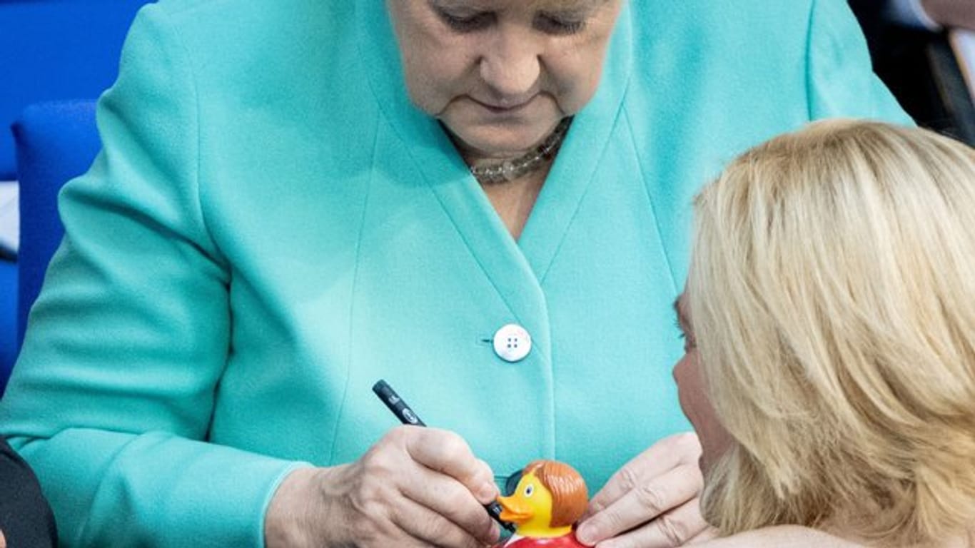 Bundeskanzlerin Angela Merkel signiert für Julia Klöckner eine Badeente.