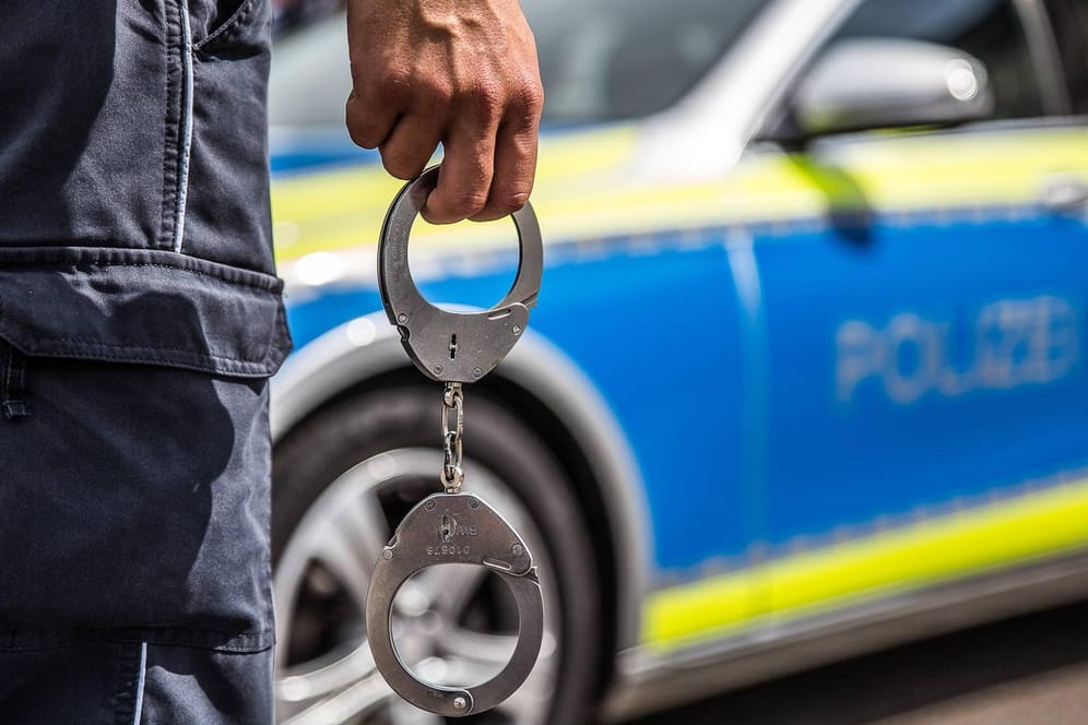 Ein Polizist mit Handschellen: DNA-Spuren haben nun zu den mutmaßlichen Tätern im Düsseldorfer Vergewaltigungsfall geführt.