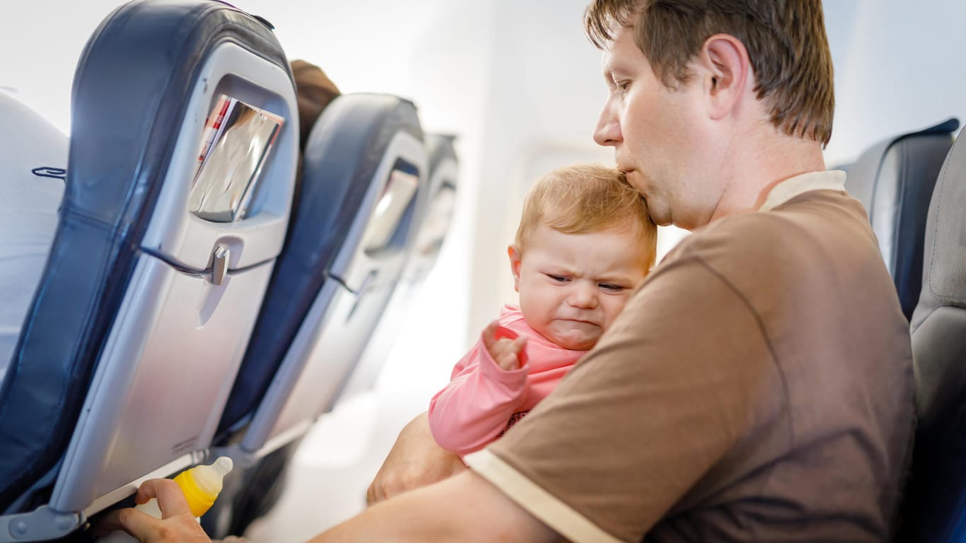 Vater mit weinender Tochter im Flieger: Japan Airlines hat sich eine Lösung für diejenigen überlegt, die auf dem Flug lieber ihre Ruhe haben.