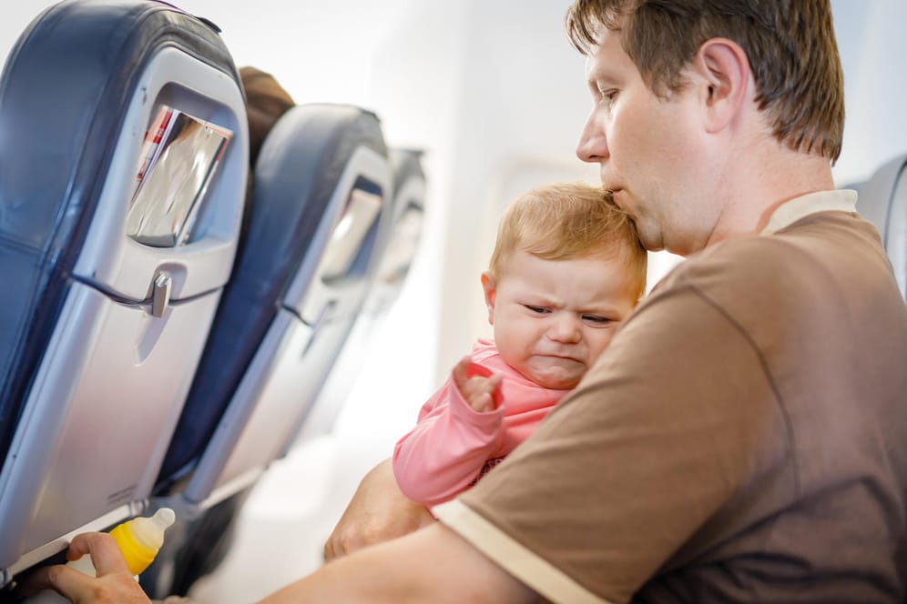 Vater mit weinender Tochter im Flieger: Japan Airlines hat sich eine Lösung für diejenigen überlegt, die auf dem Flug lieber ihre Ruhe haben.