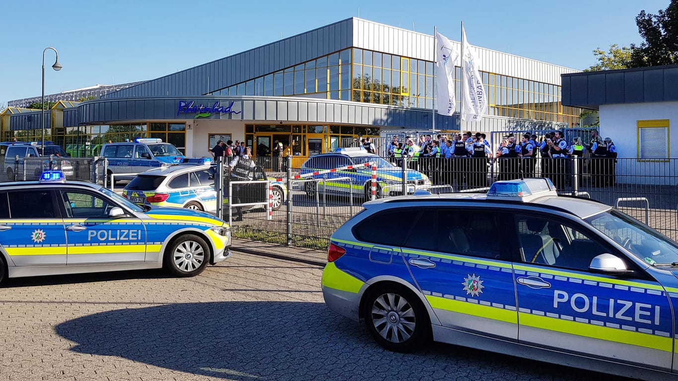 Zahlreiche Polizeifahrzeuge stehen vor dem Rheinbad: Nach der dreimaligen Räumung des Schwimmbads im Sommer enthüllt ein neuer Bericht der Stadtverwaltung Details zu den ersten beiden Tumulten.