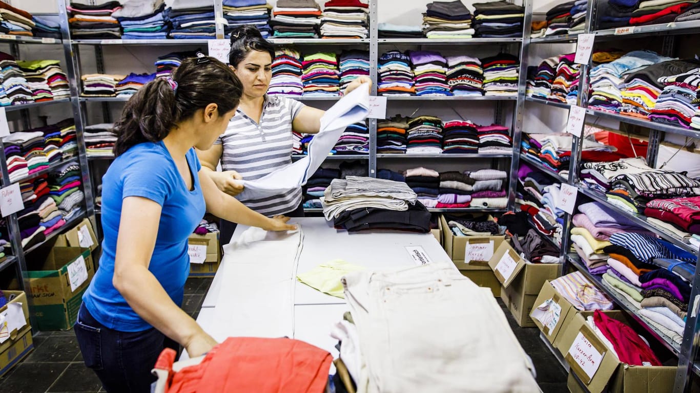 Frauen arbeiten in der Kleiderkammer einer Erstaufnahmeeinrichtung: Asylsuchende erhalten für den "persönlichen Bedarf" Sachleistungen vom Staat.