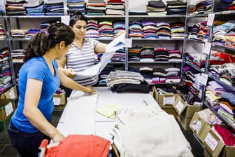 Frauen arbeiten in der Kleiderkammer einer Erstaufnahmeeinrichtung: Asylsuchende erhalten für den "persönlichen Bedarf" Sachleistungen vom Staat.