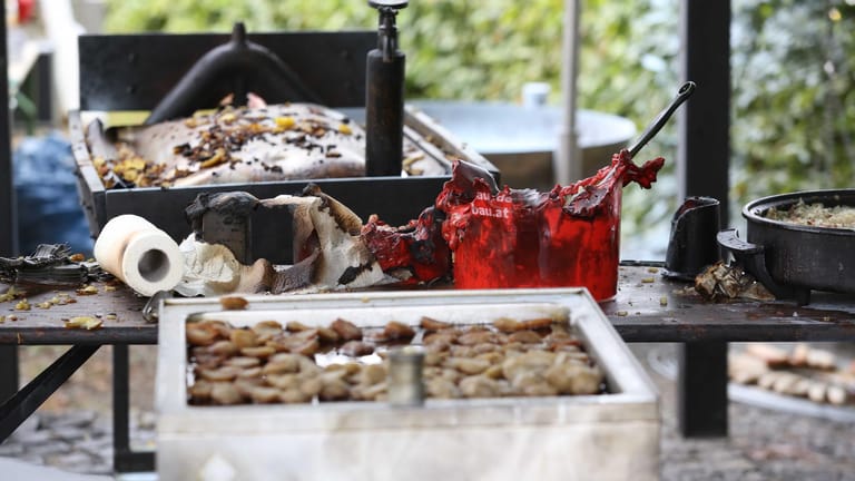 Verbrannte Grill-Utensilien sind auf einem Tisch auf dem Gelände eines Brauchtumsfestes im Siegerland zu sehen: Die Explosion einer übergroßen Bratpfanne hat ein zweites Todesopfer gefordert.