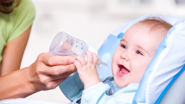 Ein Baby mit einer Trinkflasche: Kleine Kinder sollten keine zuckerhaltigen Getränke trinken.