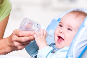 Ein Baby mit einer Trinkflasche: Kleine Kinder sollten keine zuckerhaltigen Getränke trinken.