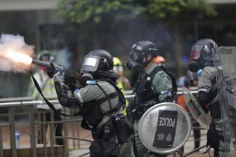 Ein Polizist setzt Tränengas gegen Demonstranten ein.