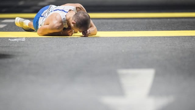 Der italienische Geher Michele Antonelli liegt im Ziel erschöpft auf dem Asphalt.