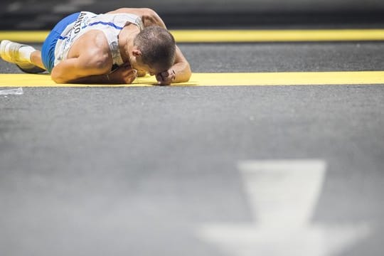 Der italienische Geher Michele Antonelli liegt im Ziel erschöpft auf dem Asphalt.