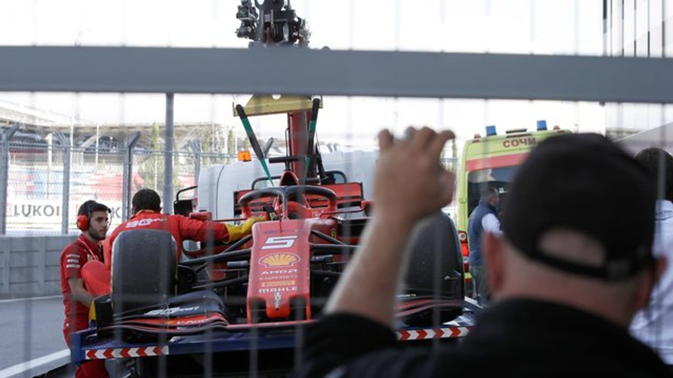 Der Rennwagen von Sebastian Vettel wird von Mechanikern vorsichtig abgeschleppt.