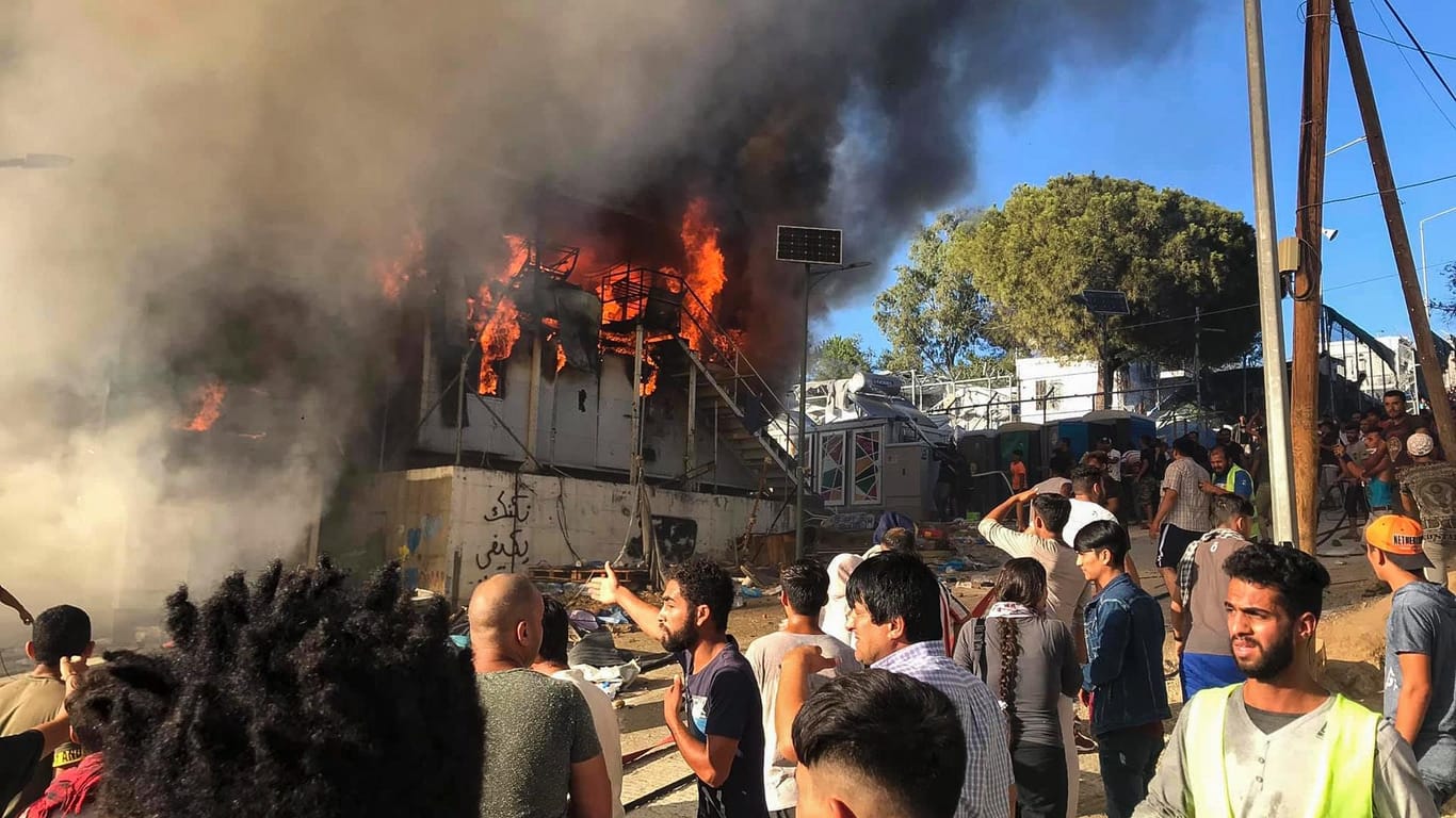Migranten auf Lesbos stehen neben einem brennenden Haus: Bei dem Brand sind mindestens zwei Menschen gestorben.
