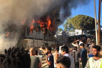 Migranten auf Lesbos stehen neben einem brennenden Haus: Bei dem Brand sind mindestens zwei Menschen gestorben.