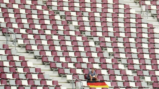 Ein Zuschauer sitzt alleine mit einer deutschen Nationalflagge auf der Zuschauertribüne im Khalifa-Stadion in Doha.