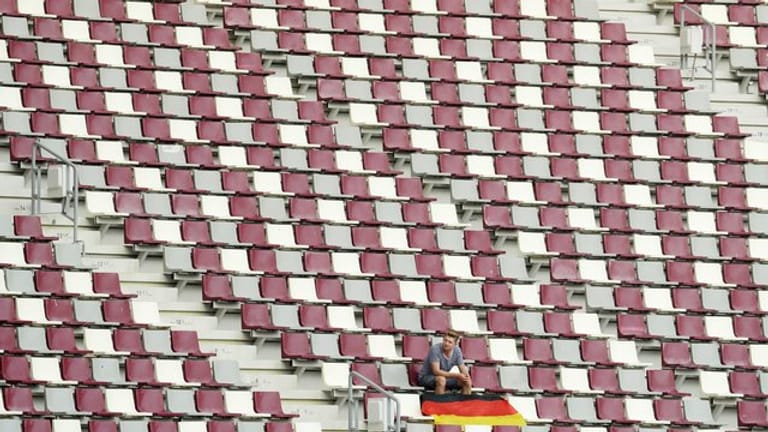 Ein Zuschauer sitzt alleine mit einer deutschen Nationalflagge auf der Zuschauertribüne im Khalifa-Stadion in Doha.