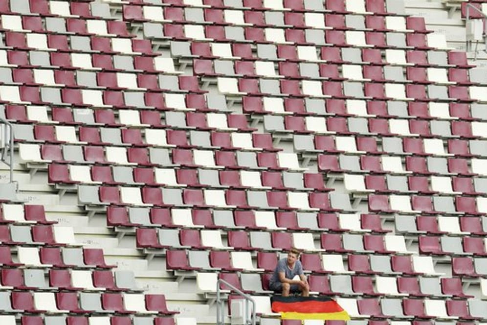 Ein Zuschauer sitzt alleine mit einer deutschen Nationalflagge auf der Zuschauertribüne im Khalifa-Stadion in Doha.
