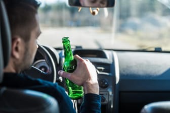 Ein Autofahrer trinkt Bier: Wer mit Alkohol am Steuer erwischt wurde, braucht oft einen Abstinenznachweis, um wieder Auto fahren zu dürfen.