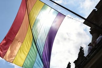 Eine Regenbogenfahne hängt an einem Gebäude.