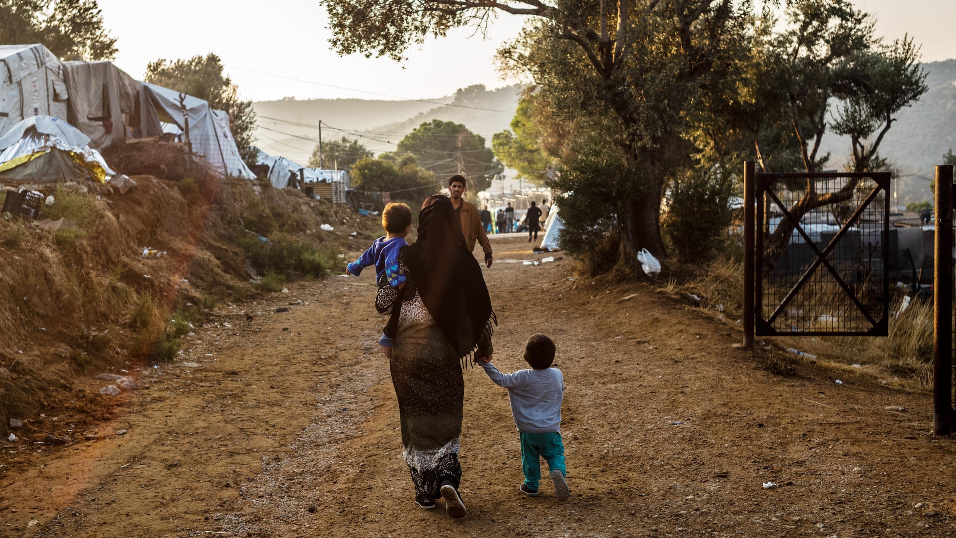 Griechenland, Moria: Ein Frau geht mit einem Kind auf dem Arm und einem anderen Kind an der Hand auf einem Weg im Flüchtlingslager Moria auf der griechischen Insel Lesbos.