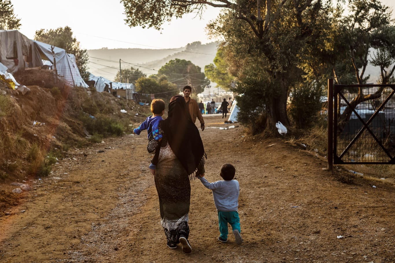 Griechenland, Moria: Ein Frau geht mit einem Kind auf dem Arm und einem anderen Kind an der Hand auf einem Weg im Flüchtlingslager Moria auf der griechischen Insel Lesbos.