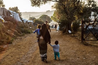 Griechenland, Moria: Ein Frau geht mit einem Kind auf dem Arm und einem anderen Kind an der Hand auf einem Weg im Flüchtlingslager Moria auf der griechischen Insel Lesbos.