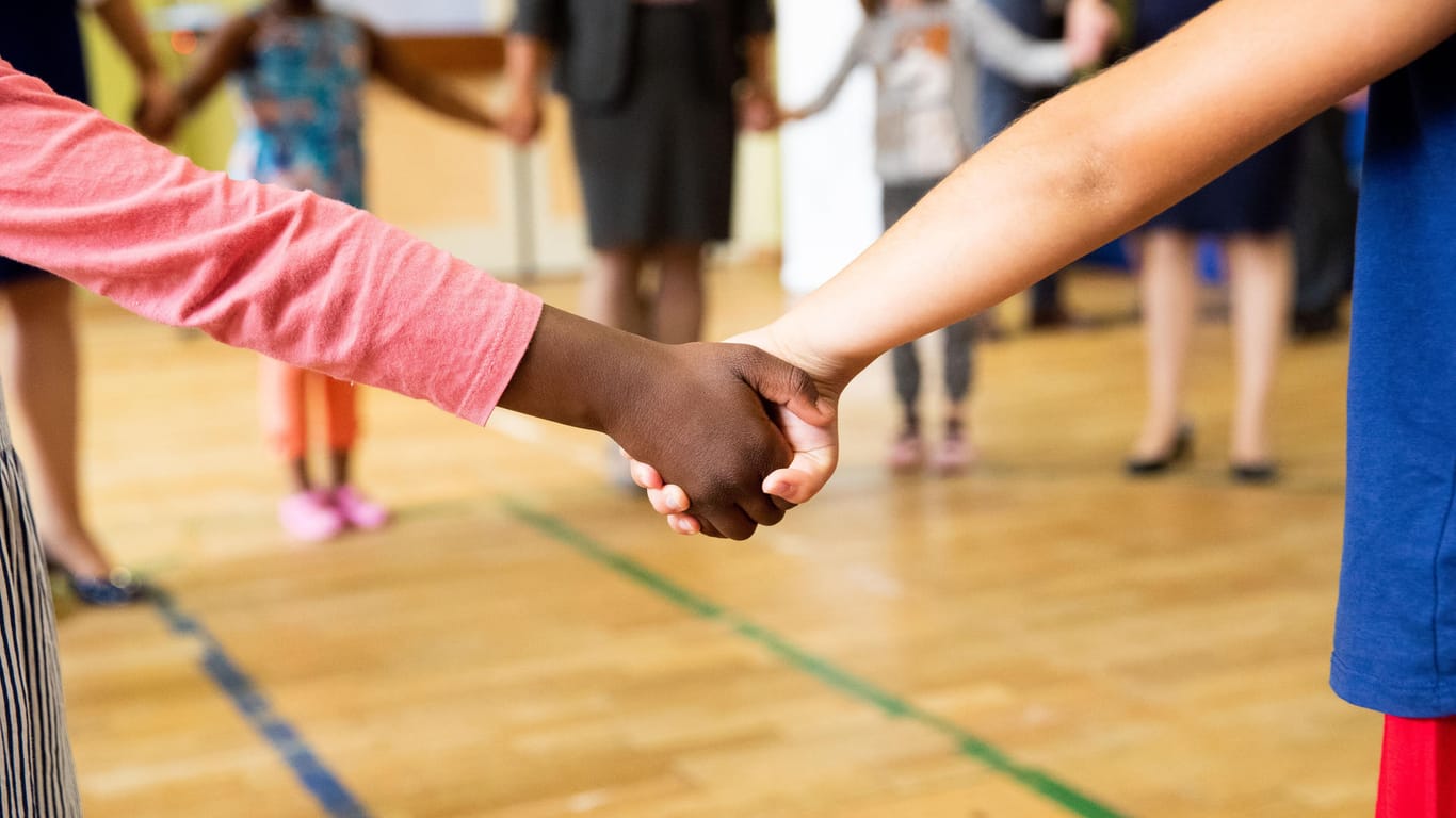 Kinder stehen Hand in Hand in einer Turnhalle (Symbolbild): Das klassische Schulfoto könnte in Zukunft komplizierter werden.