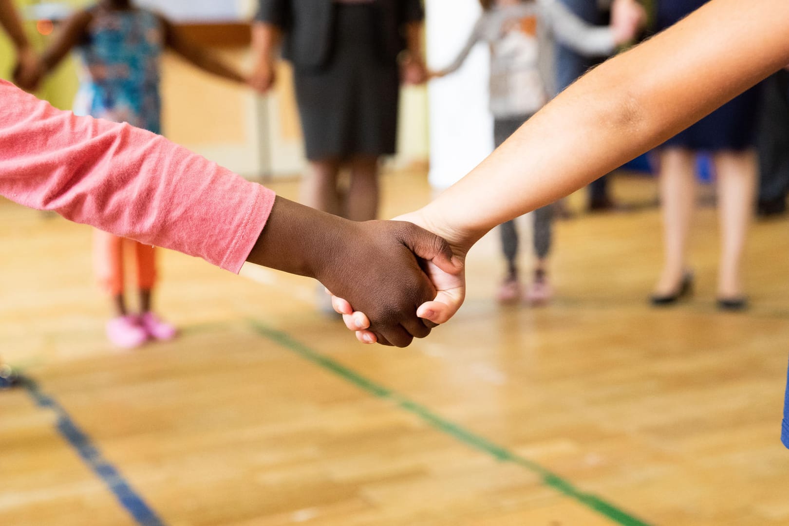 Kinder stehen Hand in Hand in einer Turnhalle (Symbolbild): Das klassische Schulfoto könnte in Zukunft komplizierter werden.
