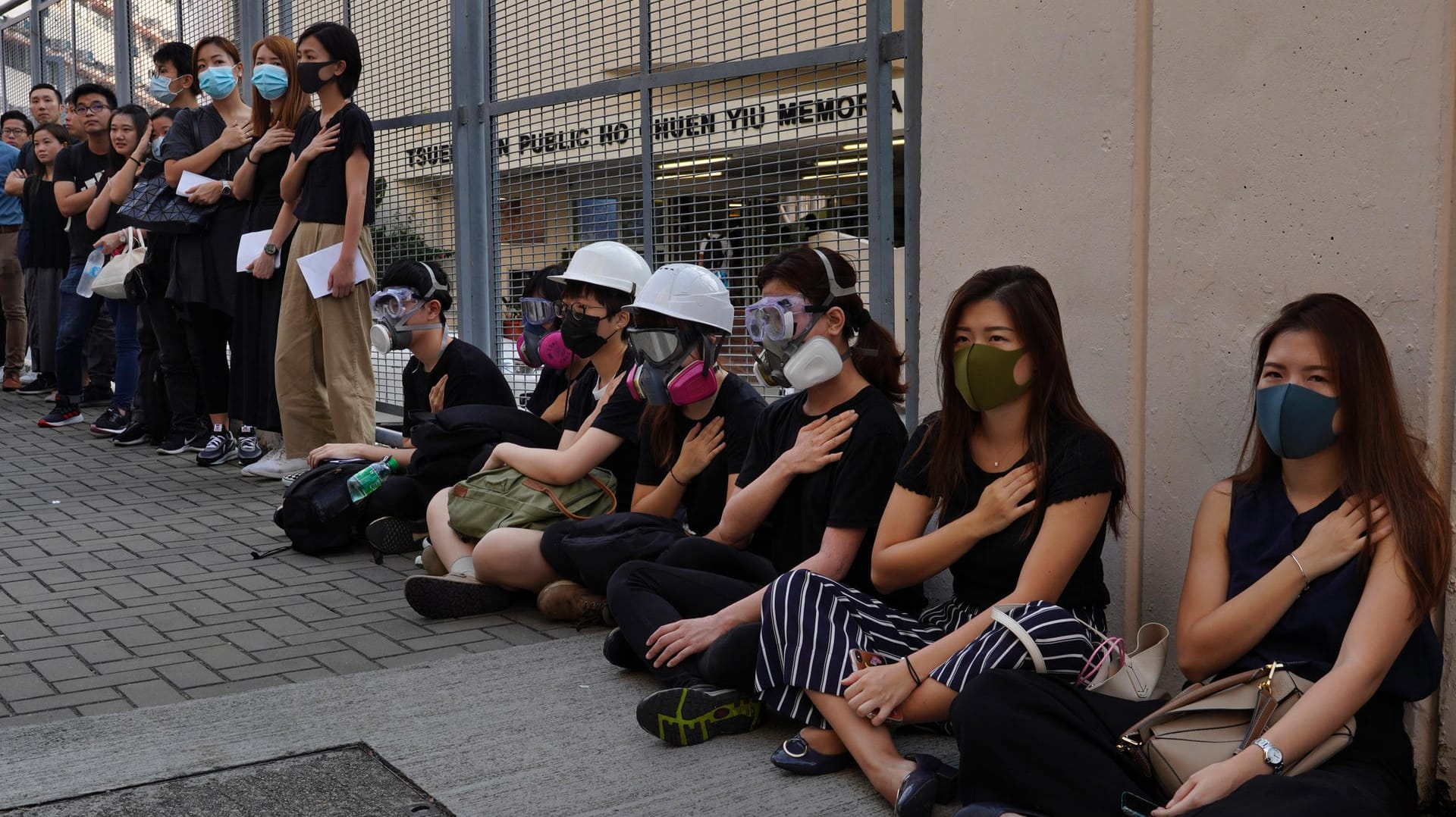 Studenten halten in einer symbolischen Geste eine Hand aufs Herz: Erstmals ist bei den Protesten in Hongkong ein Demonstrant mit scharfer Munition verletzt worden.