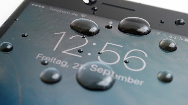 Wassertropfen auf Smartphone-Display: Moderne Geräte kommen mit wenig Wasser oft gut zurecht.