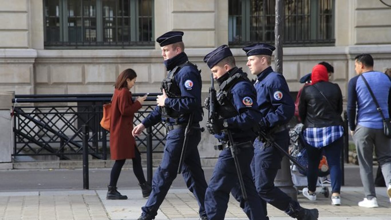 Polizeibeamte patrouillieren mit Gewehren vor dem Pariser Polizeipräsidium.