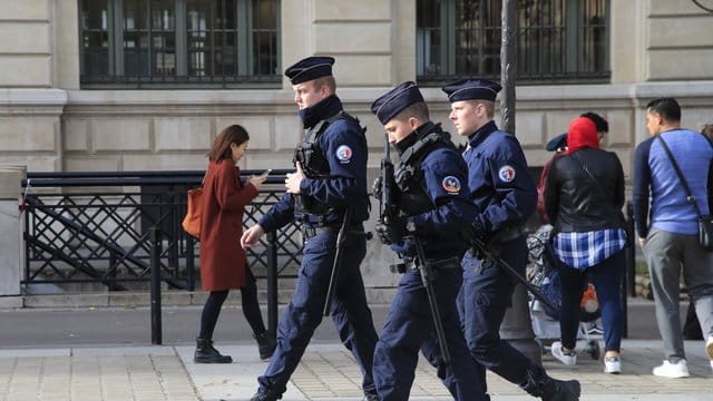 Polizeibeamte patrouillieren mit Gewehren vor dem Pariser Polizeipräsidium.