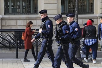 Polizeibeamte patrouillieren mit Gewehren vor dem Pariser Polizeipräsidium.