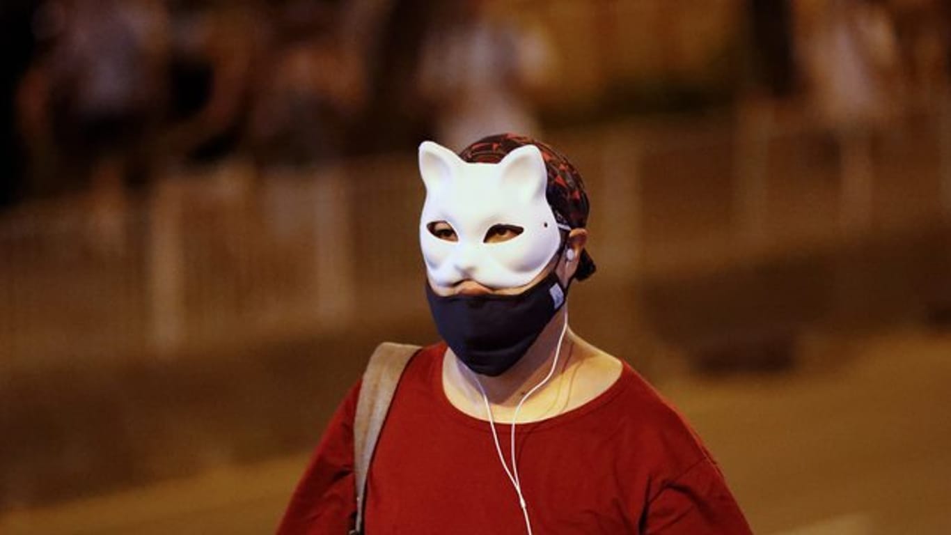 Ein maskierter Demonstrant läuft über eine Straße.
