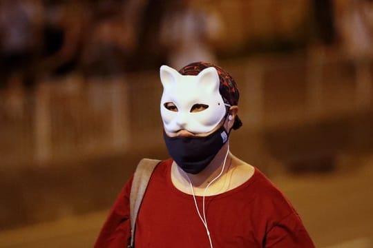 Ein maskierter Demonstrant läuft über eine Straße.