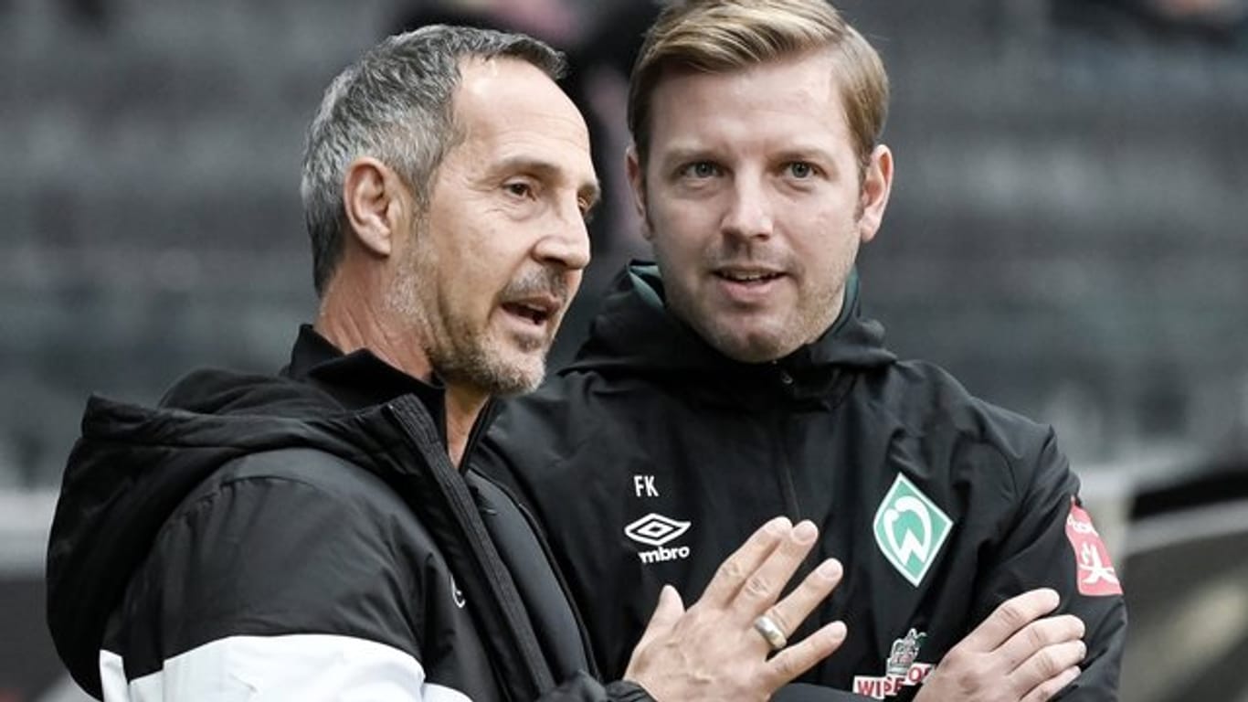 Frankfurts Trainer Adi Hütter (l) und sein Bremer Kollege Florian Kohfeldt (r) unterhalten sich vor Spielbeginn.