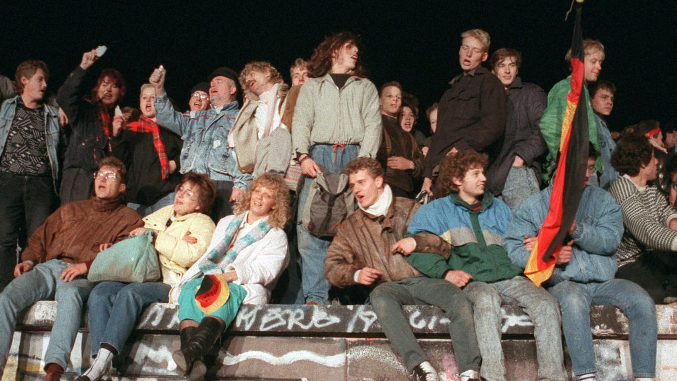 Der 9. November 1989: Singend und schunkelnd freuen sich junge Menschen über den Fall der Berliner Mauer.