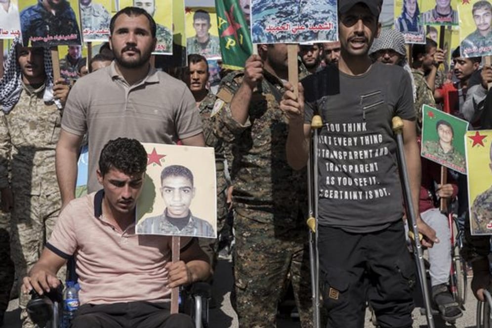 Verwundete kurdische Kämpfer präsentieren im nordostsyrischen Qamischli Bilder von Kameraden, die im Kampf gegen den IS getötet wurden.
