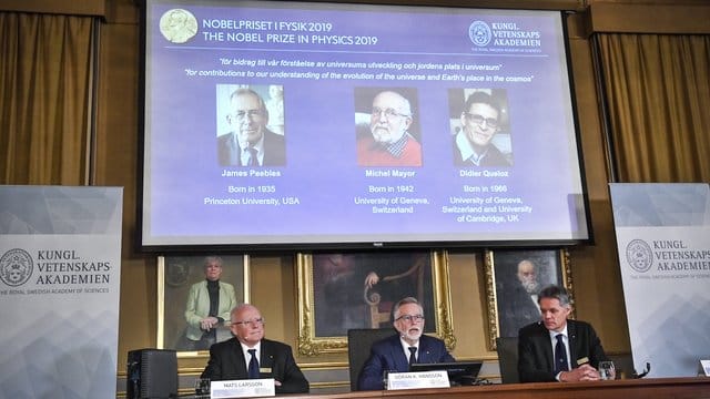 Der Nobelpreis für Physik geht in diesem Jahr an James Peebles (l-r auf der Leinwand), Michel Mayor und Didier Queloz.