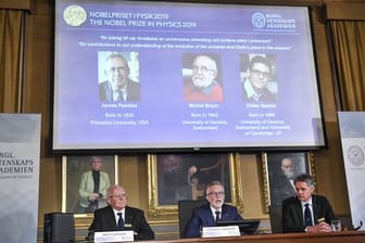 Der Nobelpreis für Physik geht in diesem Jahr an James Peebles (l-r auf der Leinwand), Michel Mayor und Didier Queloz.