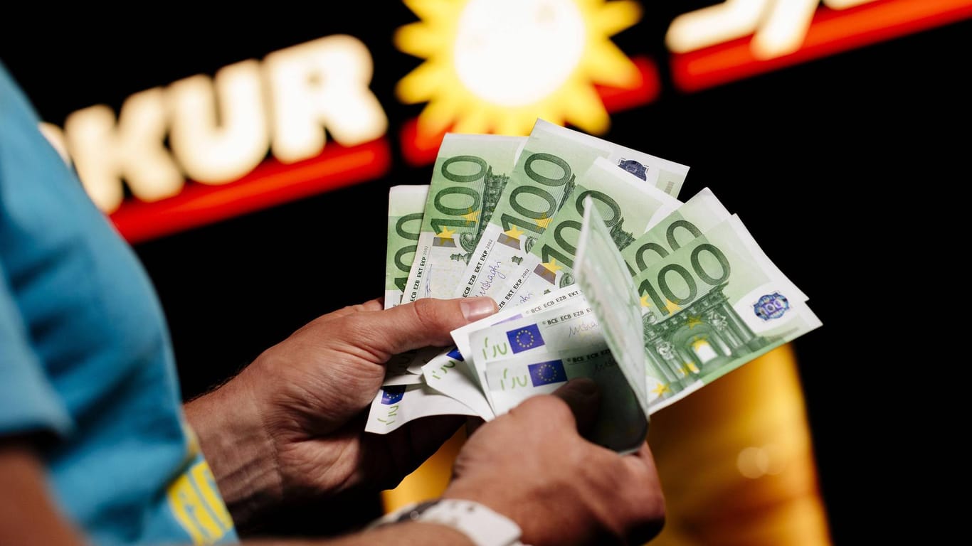 Ein Mann zählt Geld vor einer Spielothek: In Baden-Württemberg sucht die Polizei nach zwei Räubern. (Symbolbild)