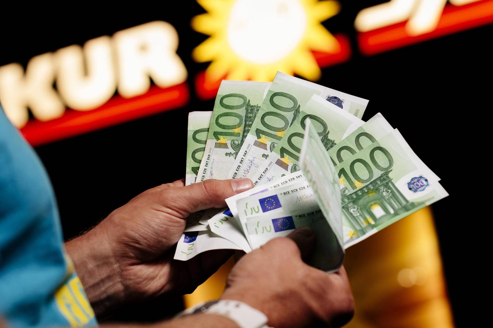 Ein Mann zählt Geld vor einer Spielothek: In Baden-Württemberg sucht die Polizei nach zwei Räubern. (Symbolbild)