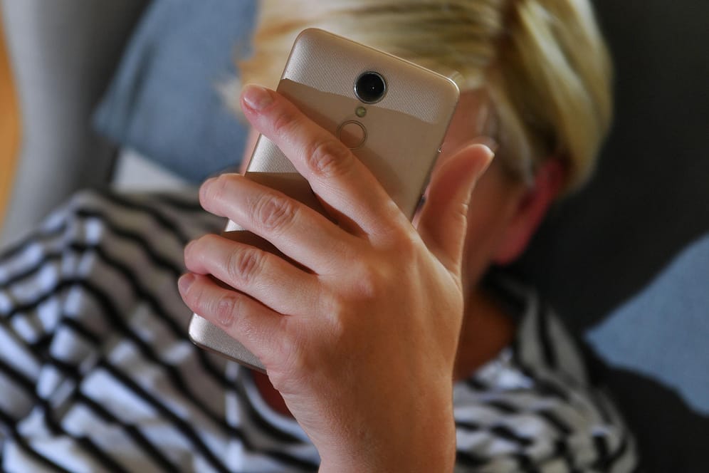 Eine Frau hält das Smartphone vors Gesicht: In Deutschland werden immer noch viele Handyverträge mit UMTS genutzt.
