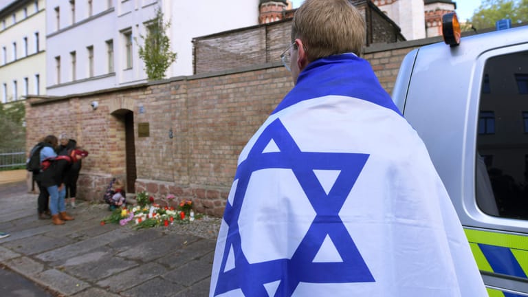 Am Tag nach dem Anschlag von Halle steht ein Junge mit einer Israel-Flagge vor dem ersten Tatort: Ein Terrorist hatte versucht, die Synagoge in Halle zu stürmen.