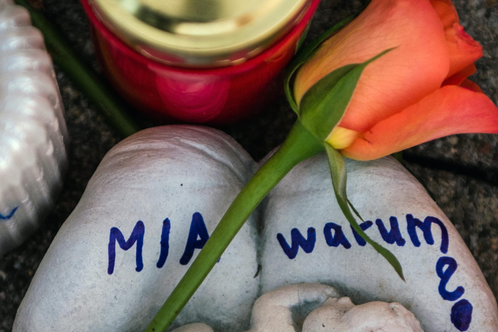 Kandel in Rheinland-Pfalz: Eine Skulptur in Form zweier Handflächen mit der Aufschrift "Mia warum?" und eine Rose liegen vor dem Drogeriemarkt, in dem ein 15-jähriges Mädchen im Dezember 2017 von ihrem Ex-Freund erstochen wurde.