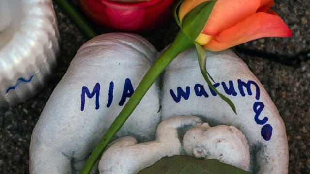 Eine Skulptur in Form zweier Handflächen mit der Aufschrift "Mia warum?" und eine Rose liegen vor dem Drogeriemarkt, in die 15-jährige Mädchen von ihrem Ex-Freund erstochen wurde. Eine Skulptur in Form zweier Handflächen mit der Aufschrift "Mia warum?" und eine Rose liegen vor dem Drogeriemarkt, in die 15-jährige Mädchen von ihrem Ex-Freund erstochen wurde.