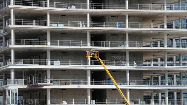 Arbeiter montieren von einer Hebebühne aus Teile an einem Neubau.