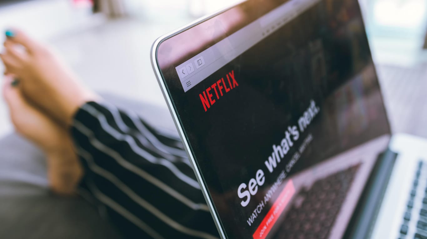 Eine Frau schaut im Bett Netflix: Der Streamingdienst hat ein paar versteckte Funktionen.
