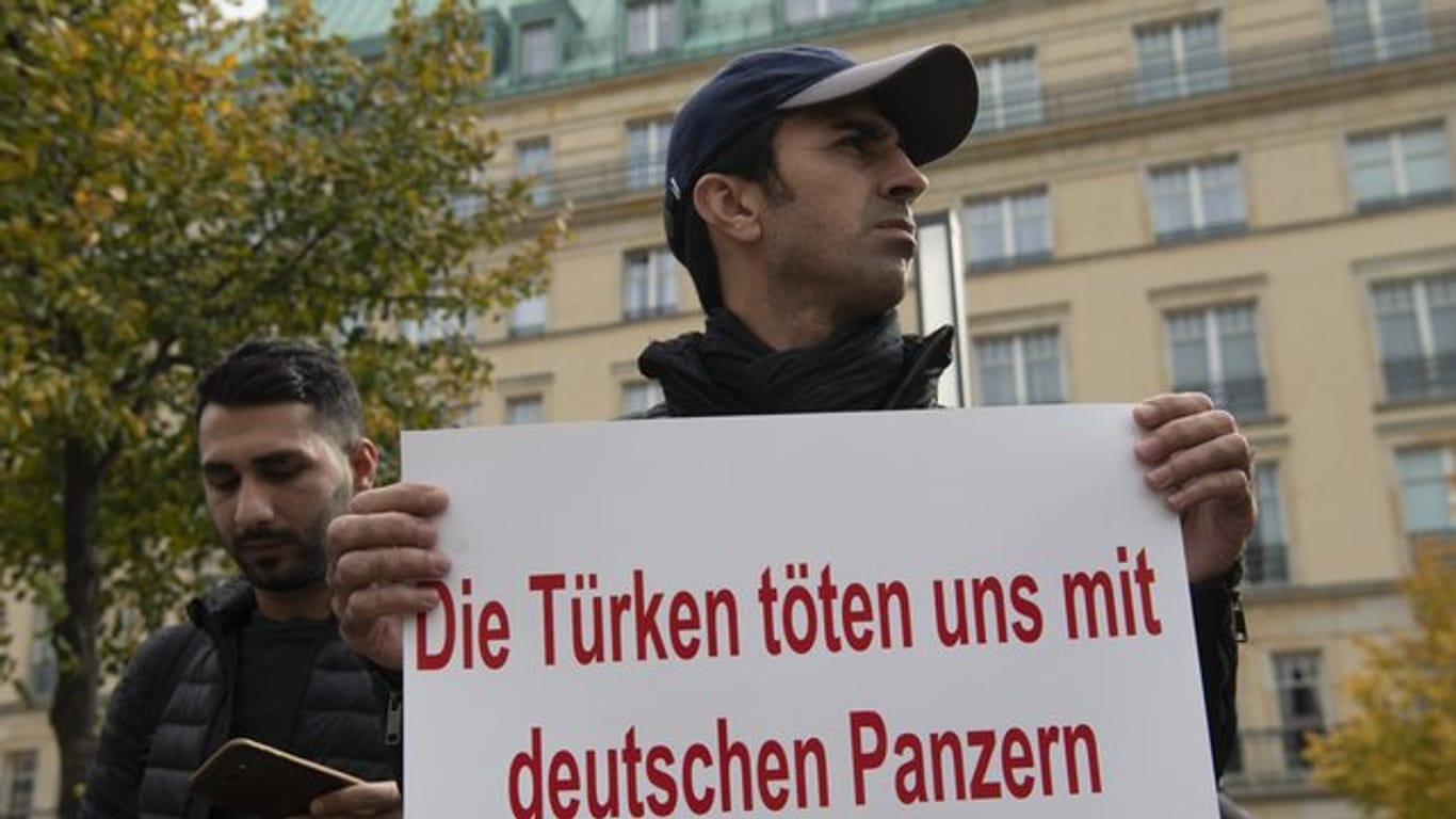 Ein Demonstrant hält bei einer Demonstration gegen die türkische Militäroffensive in Nordsyrien am Pariser Platz in Berlin ein Protestplakat.
