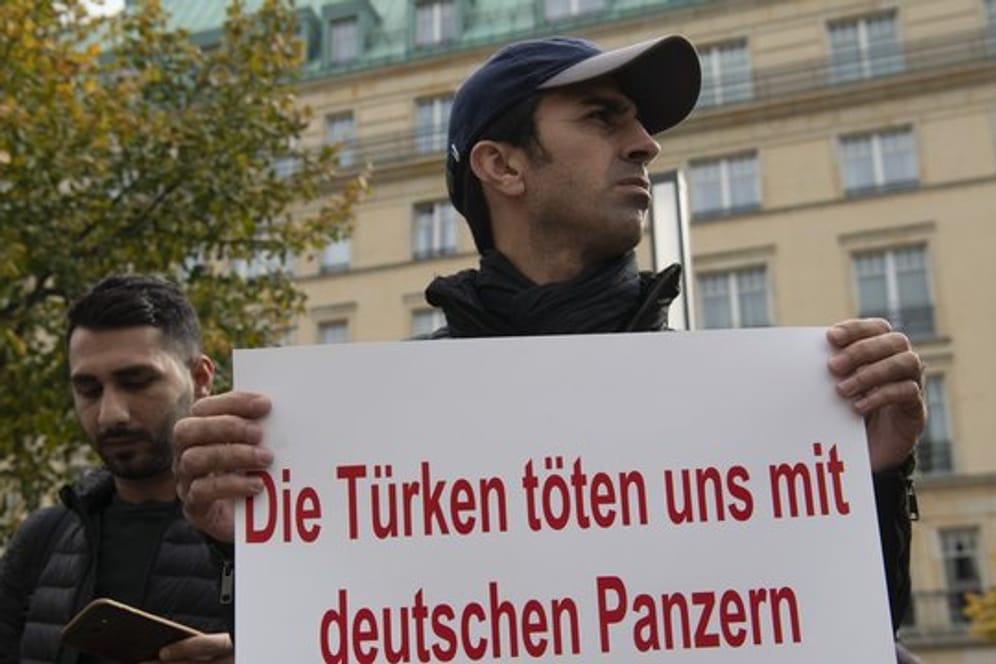 Ein Demonstrant hält bei einer Demonstration gegen die türkische Militäroffensive in Nordsyrien am Pariser Platz in Berlin ein Protestplakat.