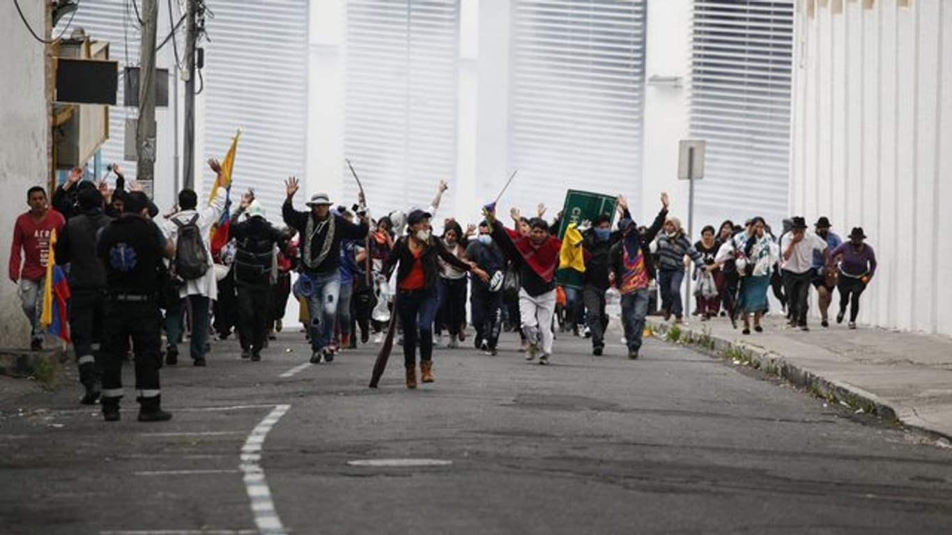 Teilnehmer einer Demonstration fliehen in Quito vor einer Wolke Tränengas.