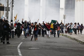 Teilnehmer einer Demonstration fliehen in Quito vor einer Wolke Tränengas.